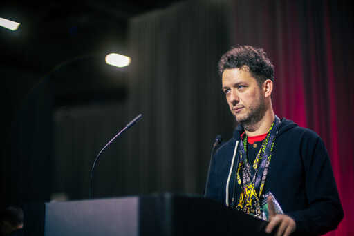 Thomas Windmill from Nautilus Institute, looking stern at a podium with red-lit black curtains behind